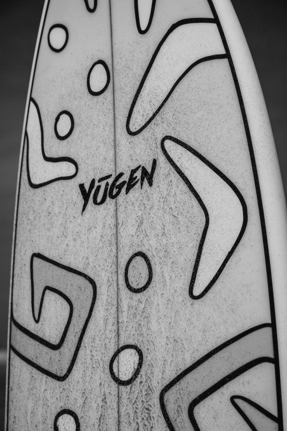 Close-up detail of a Yugen-branded surfboard deck
