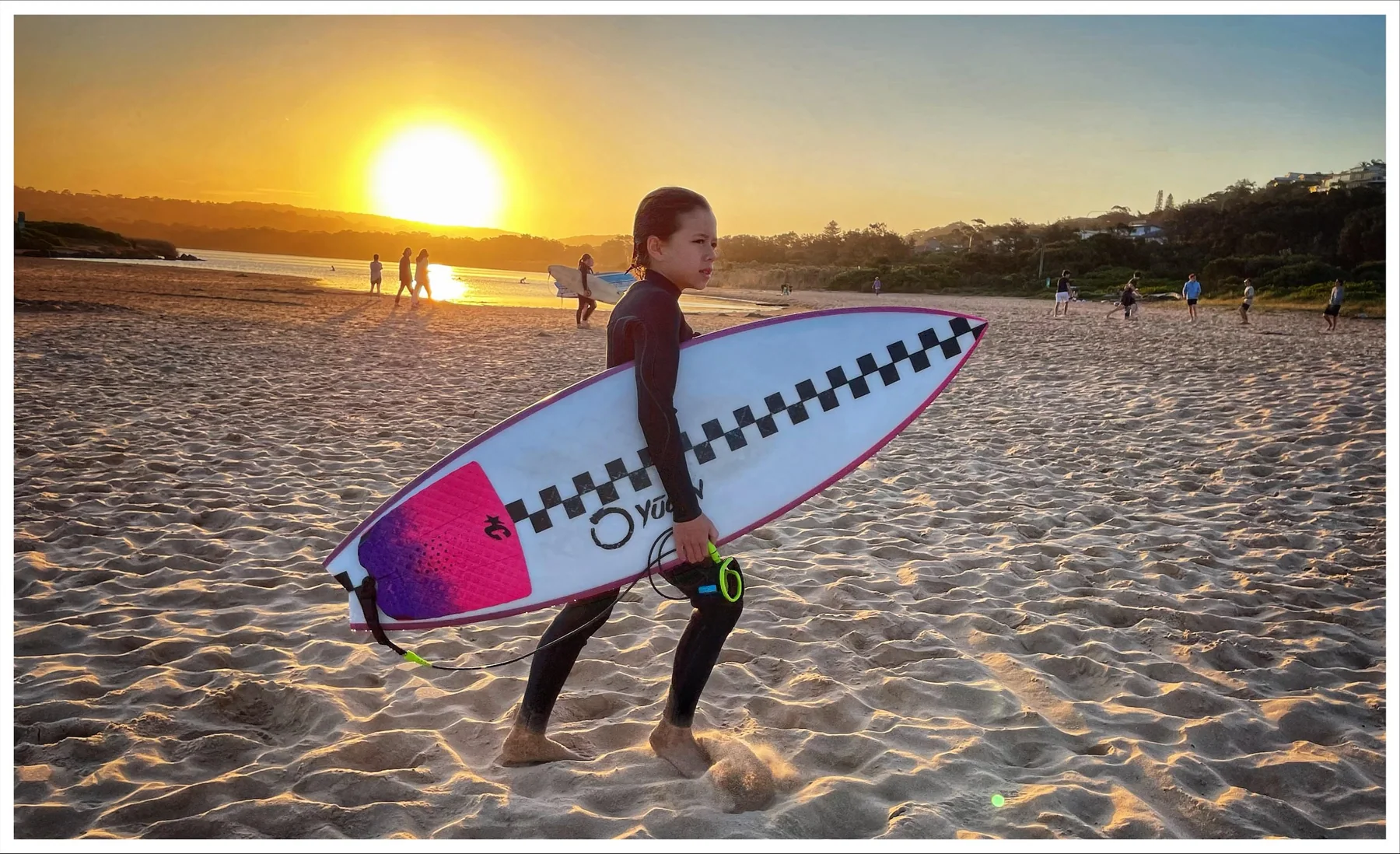 Surfer carrying a custom Yugen Wabi at sunset