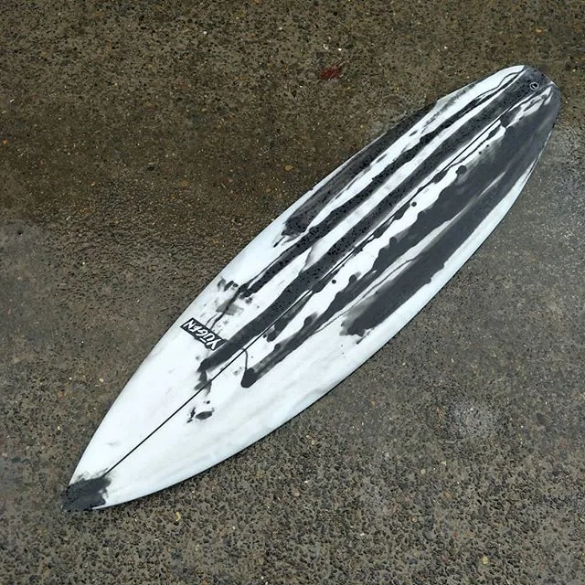 Black drip artwork on a custom shortboard