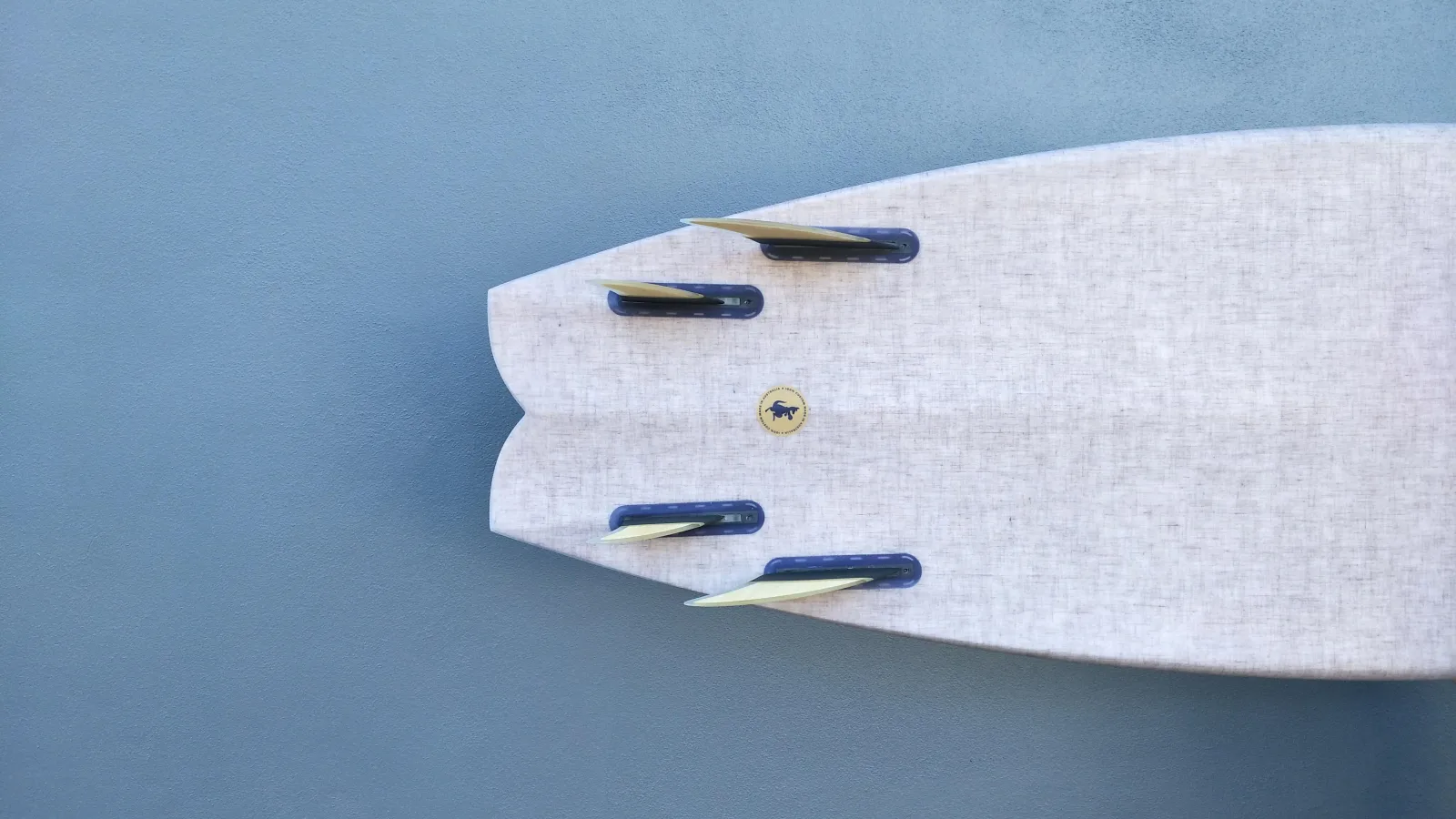 Tail of a bespoke Yugen twin-fin fish, linen-cloth finish, quad-fin setup