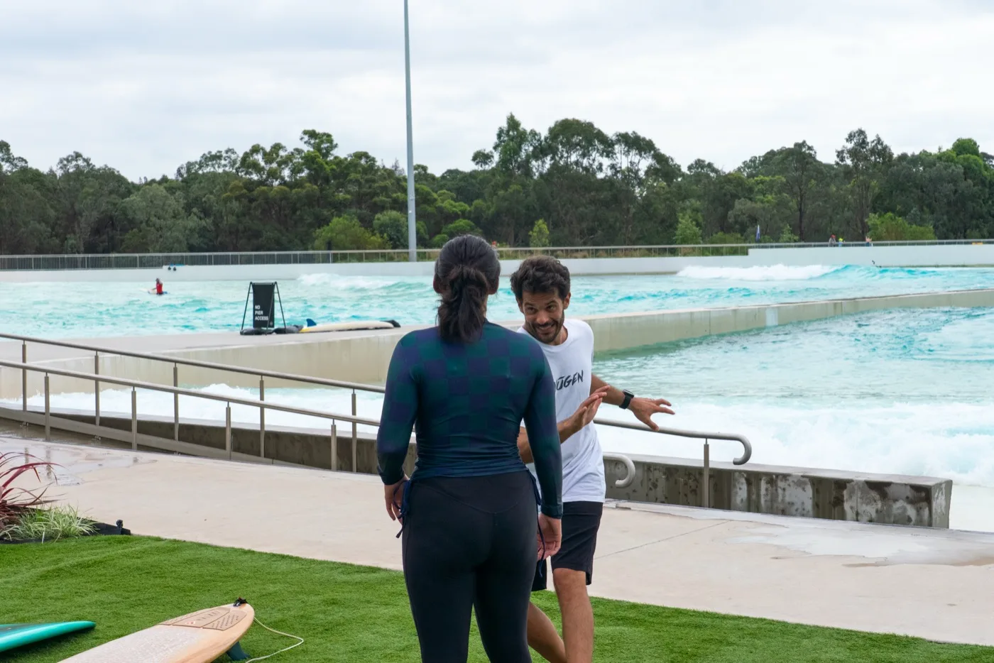 Coach and surfer talking through a movement at the wave pool